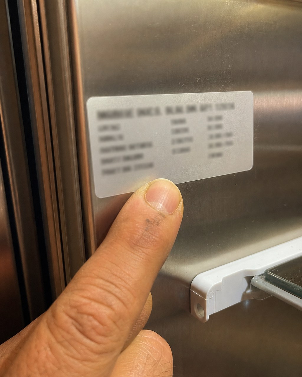 Technician pointing to the model and serial number tag inside a Sub-Zero